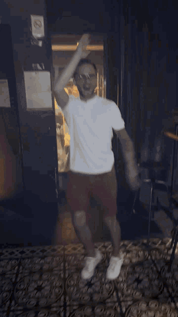 a man in a white shirt and red shorts dancing in front of a no smoking sign
