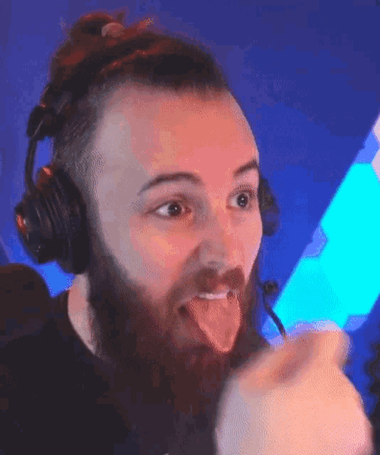 a man with a beard wearing headphones and sticking his tongue out