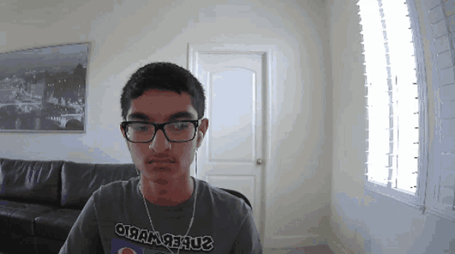 a young man wearing glasses and a t-shirt that says oi am jesus looks at the camera