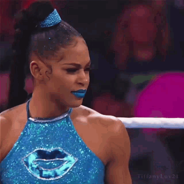 a woman in a blue wrestling outfit with blue lipstick and a tiara