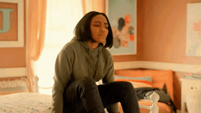 a woman is sitting on a bed in a room with a letter j on the wall .