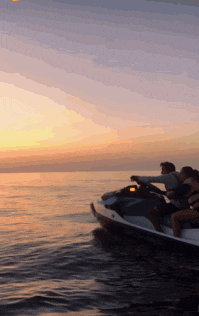 a group of people on a jet ski in the ocean at sunset
