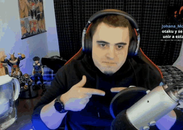 a man wearing headphones and a watch is pointing to the camera