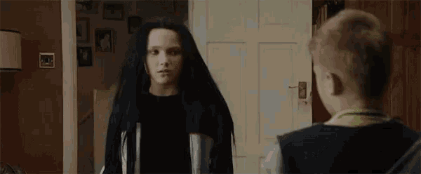 a woman is holding a cell phone and a boy is standing next to her and saying no .
