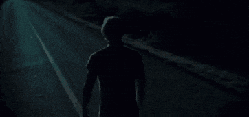 a person is walking down a dark street at night .