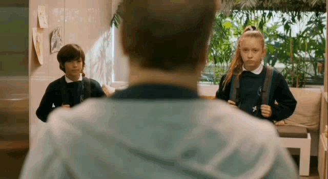 a boy and a girl are standing next to each other in a room with a man .