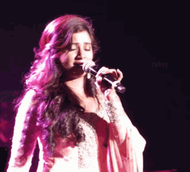 a woman singing into a microphone with rubyy written on the bottom right