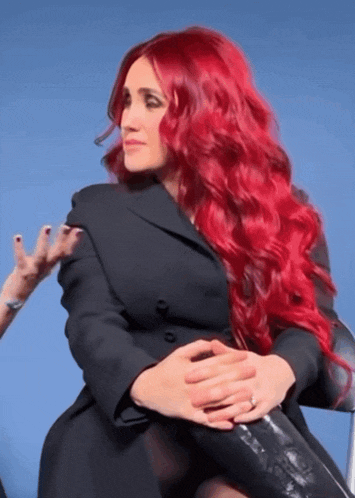 a woman with red hair is wearing a black jacket and black boots