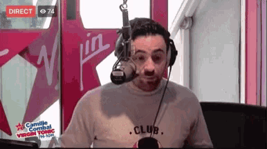 a man wearing headphones and a shirt that says club is talking into a microphone