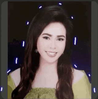 a woman with long hair is smiling for the camera while wearing a green top .