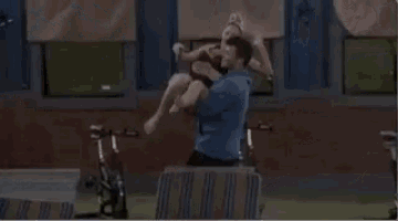 a man is holding a baby in his arms while a woman sits on a hammock .