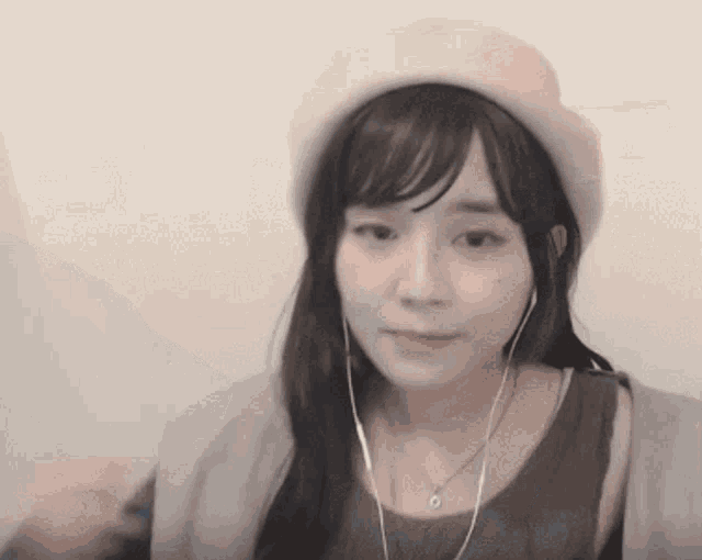 a young woman wearing a hat and earphones is looking at the camera .