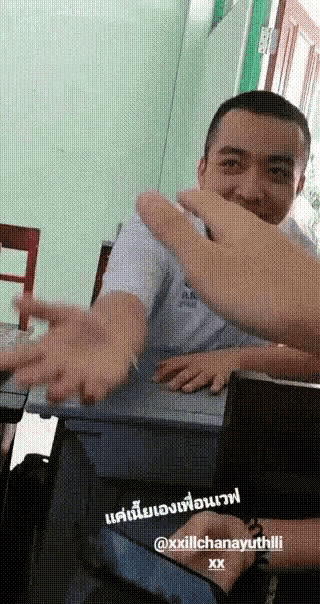 a man in a white shirt is sitting at a desk with his hands out