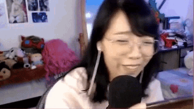 a woman wearing glasses and headphones is holding a microphone in front of her face .