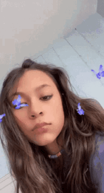 a girl with long hair and blue butterflies on her face .