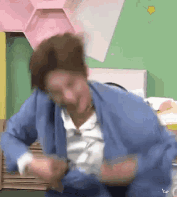 a man in a blue sweater is making a funny face .
