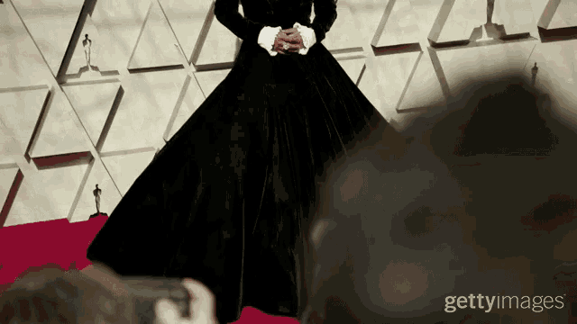 a person taking a picture of a woman in a black dress with getty images on the bottom right