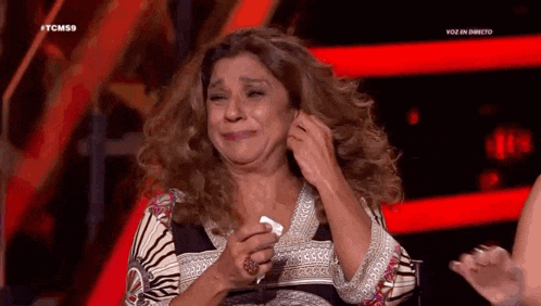 a woman is crying on a stage while holding a tissue in her hand .
