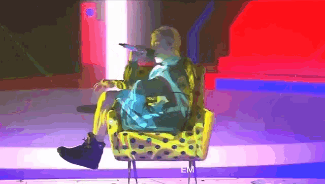 a person in a spongebob costume is sitting in a chair with a microphone
