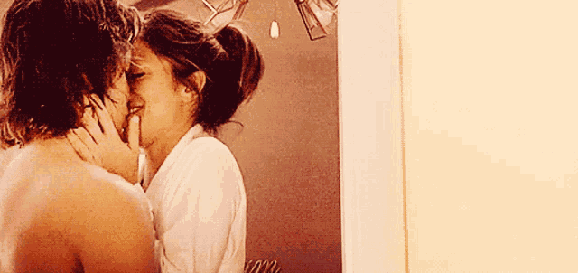 a man and woman are kissing in front of a mirror in a bathroom .