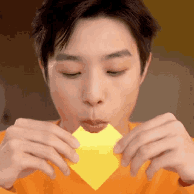 a close up of a person eating a piece of yellow paper