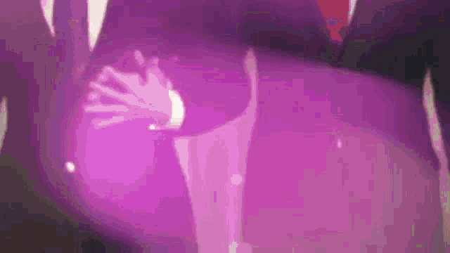 a man in a suit and tie is clapping his hands together in front of a purple background .
