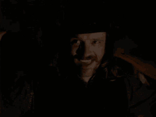 a man with long hair and a beard is screaming in the dark