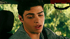 a young man is sitting in the back seat of a car looking at something .