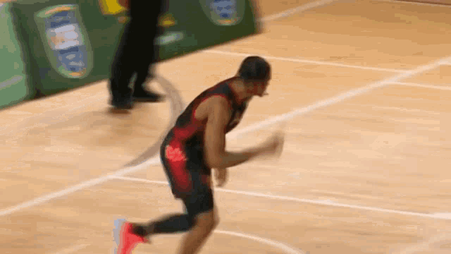 a basketball player in a red and black uniform is running on a court