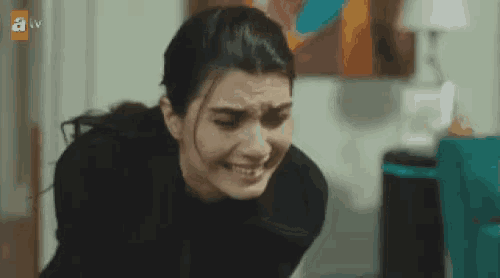 a woman is crying in a room with a tv behind her