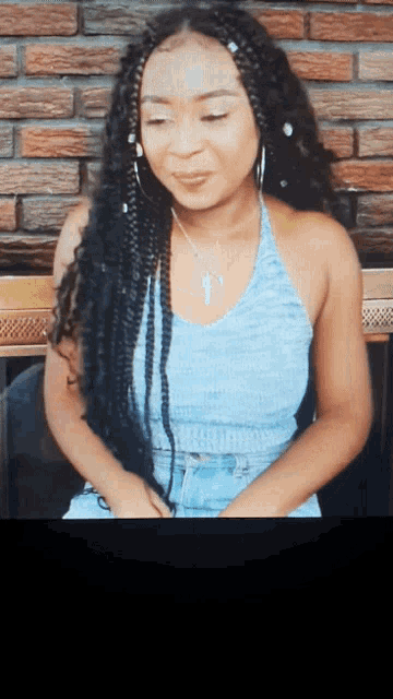 a woman wearing a blue tank top with braids and a key necklace
