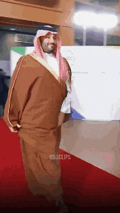 a man in a traditional costume is walking on a red carpet