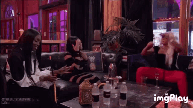 a group of women are sitting on a couch and a table with bottles of water