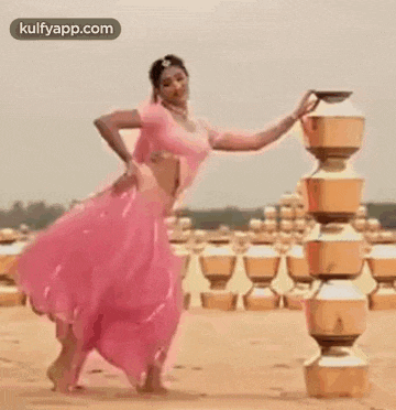 a woman in a pink dress is standing in front of a stack of pots .