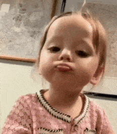 a little girl is making a funny face while making a funny face .