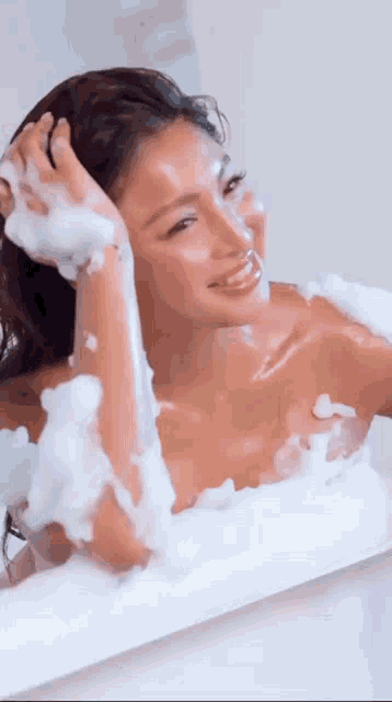 a naked woman is taking a bath in a bathtub filled with foam