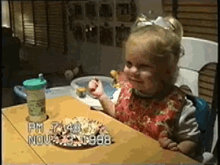 a little girl is sitting at a table with a cup on it that says pm 7 : 48 nov 23 1998