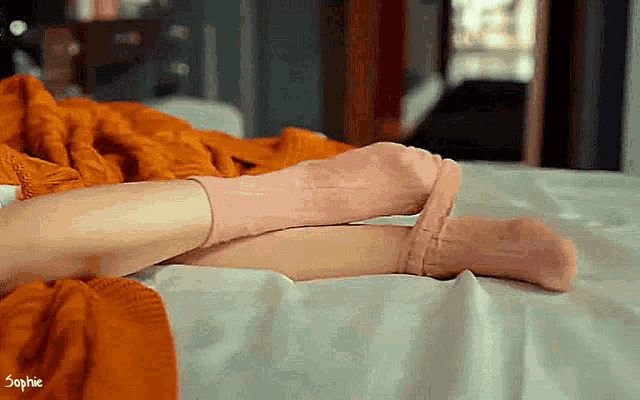 a woman wearing pink socks is laying on a bed with the name sophie on the bottom