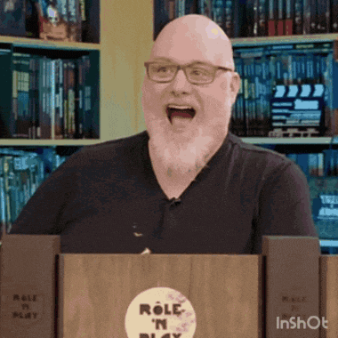 a bald man with glasses and a beard is standing behind a podium that says role in play