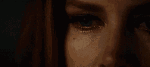 a close up of a woman 's eyes with tears running down her face .