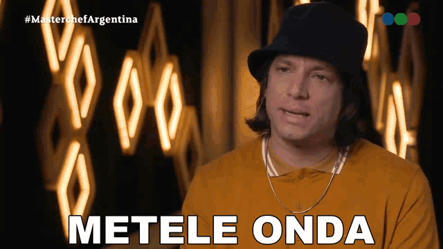 a man wearing a hat says metele onda in front of a neon sign