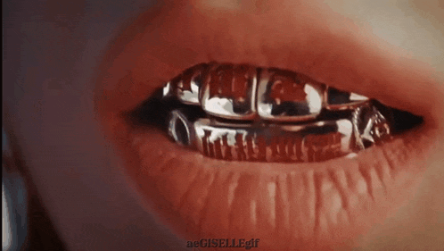 a close up of a person 's mouth with gold grills on it .