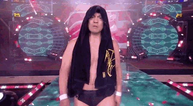 a wrestler is standing on a stage with a towel around his head .