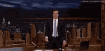 a man in a suit and tie is standing on a stage in front of a city .