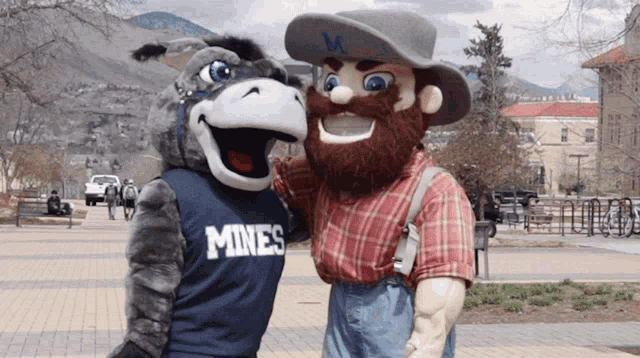 a donkey mascot and a cowboy mascot are posing for a photo