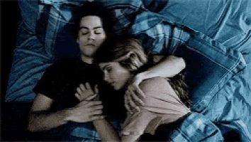 a man and a woman are sleeping in a bed together .