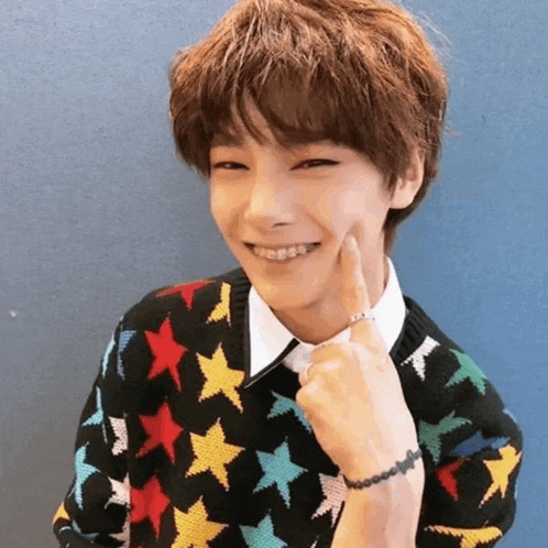 a young man wearing a colorful sweater with stars on it