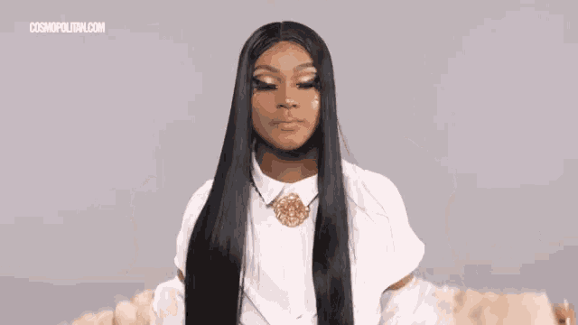 a woman with long black hair is wearing a white fur coat and a white shirt .