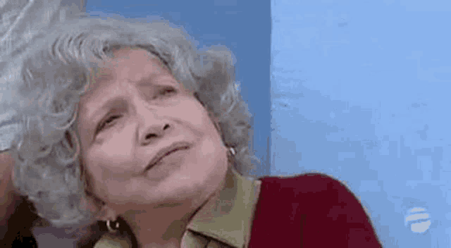 an elderly woman with gray hair and earrings is looking up at the sky .