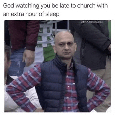 a bald man in a plaid shirt and vest is sitting in a crowd of people .